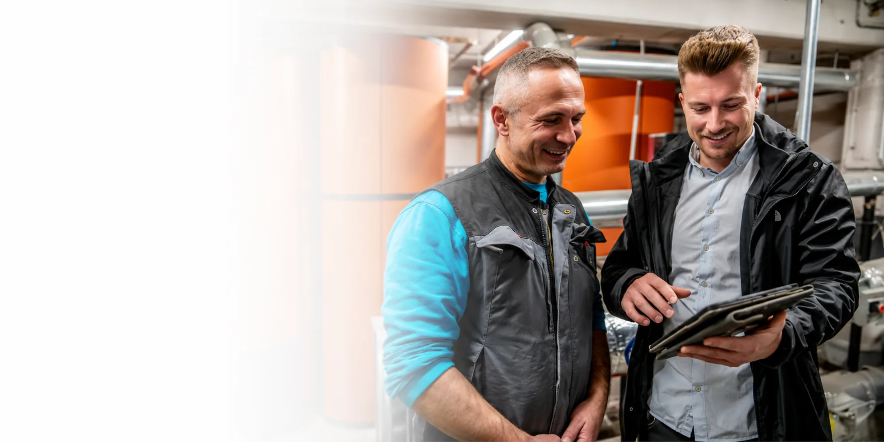 Zwei Berater besprechen einen Sachverhalt anhand eines Tablets in einer technischen Anlage